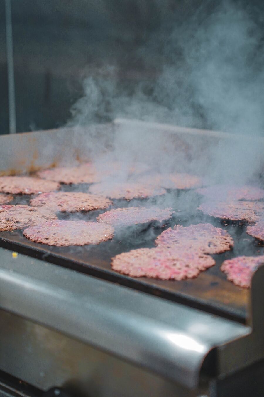 Smash patties searing on the flat top